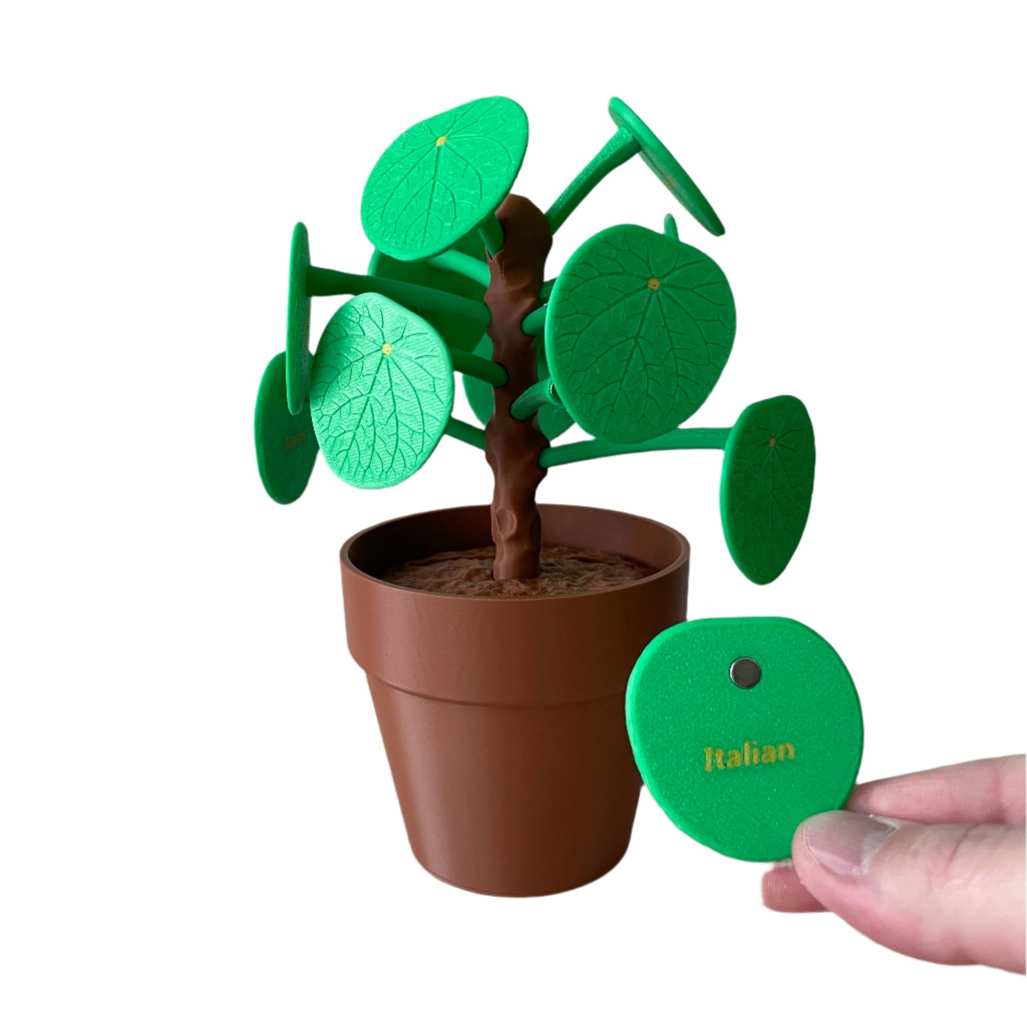 Small 3d printed pilea potted plant with green leaves and a brown pot on a white surface.